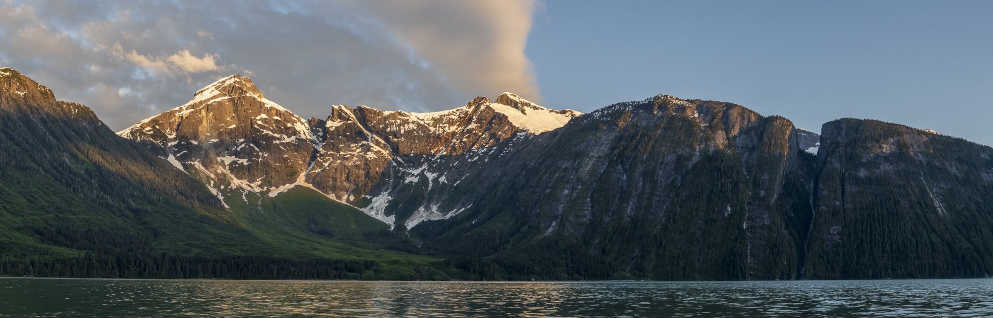 The sun just touches the alpine slopes of Three Finger Peak and Mount Kennedy in Knight Inlet's Glacier Bay.